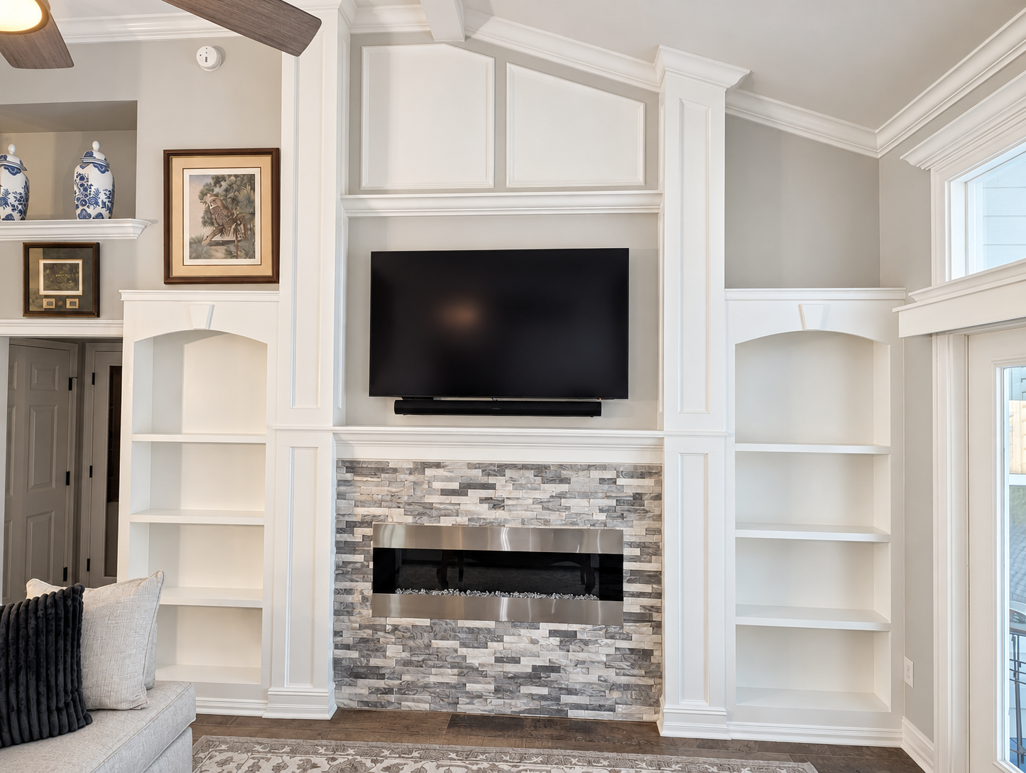 Custom white built-ins framing a stone fireplace with detailed crown molding